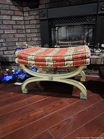 Side view of wood frame bench with upholstered cushion showing decorative curved legs and medallion detail.