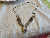 Photo of entire cameo necklace with purple stones and central carved cameo.
