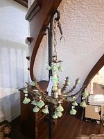 Overall view of the chandelier suspended from a stand, showing flower pendants and metal arms.