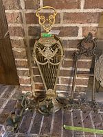 Image showing a tall ornate brass fire screen with intricate floral and shield designs, alongside other fireplace items.