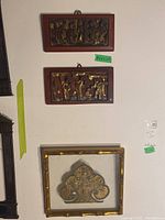Overall view of two carved wood plaques and framed embroidery