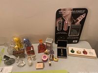 Lot of perfume bottles arranged on a table including atomizer set, decorative bottles, and miniature boxed set.