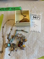 Photo of multiple silver jewelry items including turquoise beaded necklace with charms and a teardrop pendant necklace in a box.
