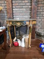Front view of the wooden console table showing floral painted details and glass top.