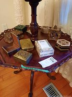 View of all trinket boxes arranged on a carved wooden round table under a lamp.