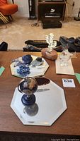 Overall lot view on table showing blown glass fish, jade bear carving, agate slice, small globe on mirrored trays