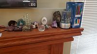 Wide view of the collectibles displayed on wooden mantle including geode slices, crystal sculpture, ornaments, and knick knacks.