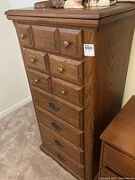 View of the dresser from an angle showing its tall, narrow form and the mix of round knob and decorative handles on drawers.