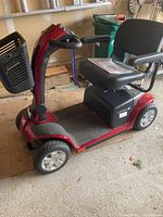 Front and side view of red and black Pride Mobility scooter with front basket and swivel seat