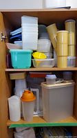 Two shelves full of assorted plastic vintage and modern food storage containers in various shapes and colors.