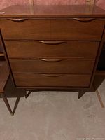 Front elevation of four-drawer dresser showing integrated recessed pulls and angled legs.