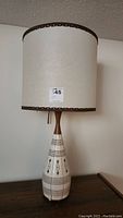 Full view of mid century modern ceramic and wood table lamp with paper shade.