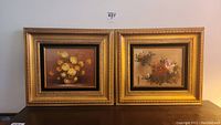 Pair of two original floral paintings side by side in matching ornate gold toned frames on a wall.