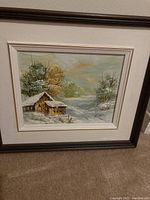 Full view of framed painting showing cabin, snowy trees, and winter landscape.