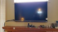 Front view of the Sony Bravia TV mounted on the wall above a wooden mantel with various decorative items.
