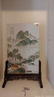 Front view of painted glass panel on carved wood stand