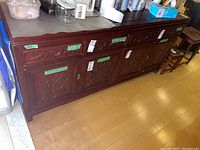 Full view of long wood cabinet showing four drawers above four carved doors