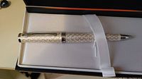 Top view of the silver-tone Cross pen with circle pattern in box, showing pen and clip details.