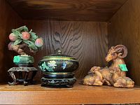 Photo of a stone fruit tree sculpture with pinkish fruit on a wooden shelf.