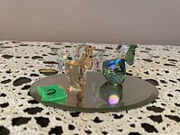 Overview of two Swarovski crystal horses on the round mirror base on lace fabric background, showing their size and sparkles.