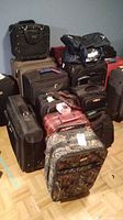 Multiple luggage items of various brands stacked together, showing different shapes and colors.
