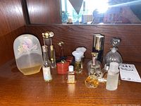 Overview of multiple assorted vintage perfume bottles on wooden surface