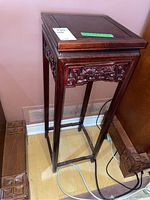Full view of tall carved wood stand showing square top and legs