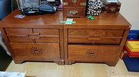 Pair of matching wooden bedside tables with carved drawer details and two drawers each.