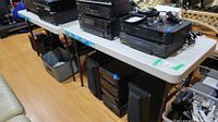 Both plastic folding tables shown with various audio equipment on top in basement room