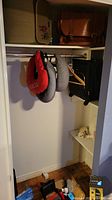 View of hanging red and grey neck roll pillows, black bag on hanger, and floor with small travel accessories.