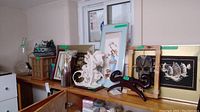 Wide view of all items on shelves including figurines, framed art, mask and other decorative pieces.
