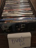 Two stacks of DVDs showing multiple movie titles in cases including The Hitcher, American Gangster, I Am Legend, Hancock, Saw IV, Million Dollar Baby, Eagle Eye among others.
