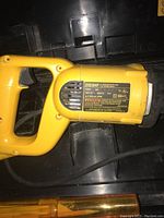 Close-up photo of DEWALT DW304P saw body with label visible, showing model and electrical info. Yellow saw handle and casing visible resting in molded black plastic case.