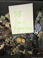 Photo of 35 Black figurines with various colors and poses laid out, showing a handwritten sign indicating quantity and description.