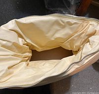 Interior of a cream-colored fabric carrying bag with zipper, showing empty space inside