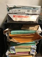 Image showing stacked packs of colored paper in green, orange, yellow, and pink partially wrapped in packaging