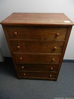 Front view of the solid wood dresser showing 5 drawers with wooden knobs and some surface wear.