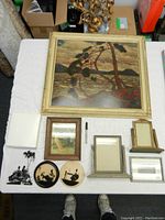 Full view of the large framed print and smaller frames and silhouette art pieces arranged on white cloth
