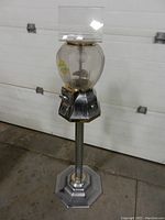 Full view of candy vending machine, showing overall design with globe top and metal stand