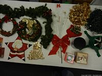 Top view of assorted Christmas decorations laid out on table including wreaths, garlands, bows, signs, and holiday figure decor.