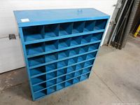 Front perspective of blue metal cubby shelf showing multiple cubby holes for parts storage.