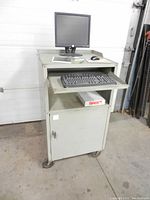 Front view of portable computer station showing monitor, keyboard tray, top angled surface, and caster wheels.