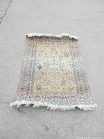 Full view of the decorative rug with detailed floral and geometric pattern and fringed edges lying on pavement