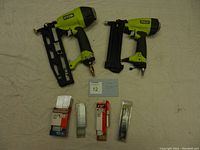 Two Ryobi pneumatic nailers (large and small) laid out with packs of nails
