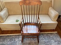 Front view of antique rocking chair showing vertical spindle backrest, seat, and armrests.