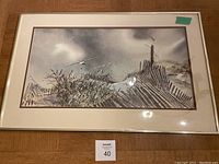 Full view of framed coastal scene print with sand dunes, fences, seagulls under cloudy sky.