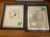 Two black-framed abstract botanical prints side by side, each with white matting and green price tags.