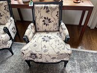 First bergere chair showing floral upholstery with black wooden frame and sun damage