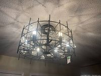 Chandelier illuminated from below showing the pattern cast on ceiling and glass accents inside black metal framework.