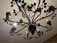 View looking up at the chandelier showing its leaf branch design and 8 candle-style holders.